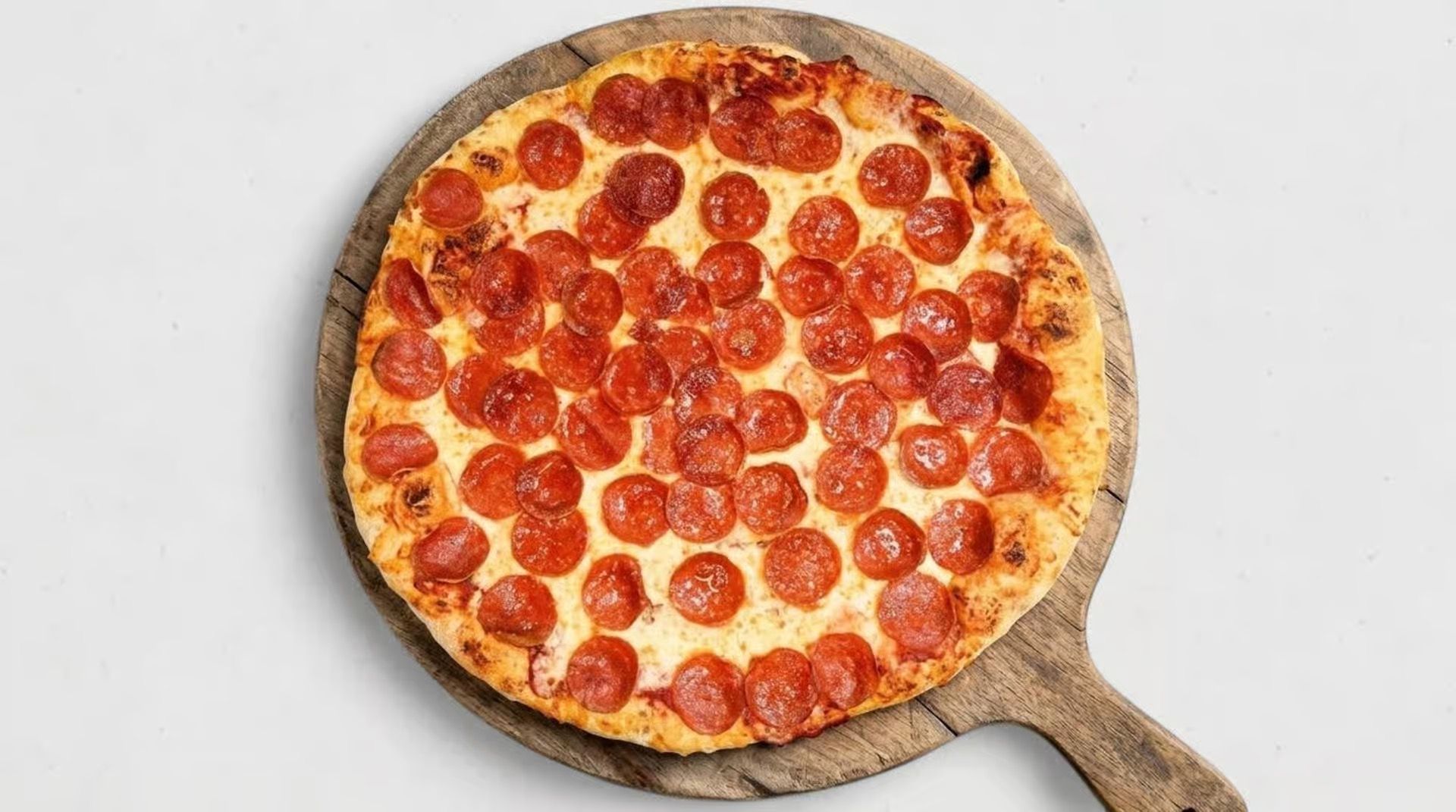 Pepperoni pizza in a round pan with a handle, viewed from above on a white background