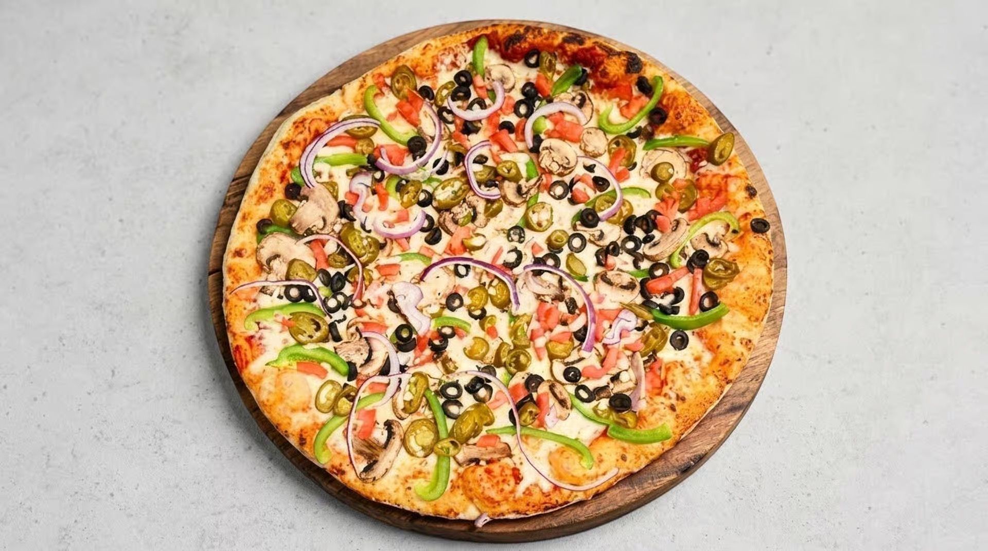 Top-down view of a colorful vegetable pizza on a light gray surface