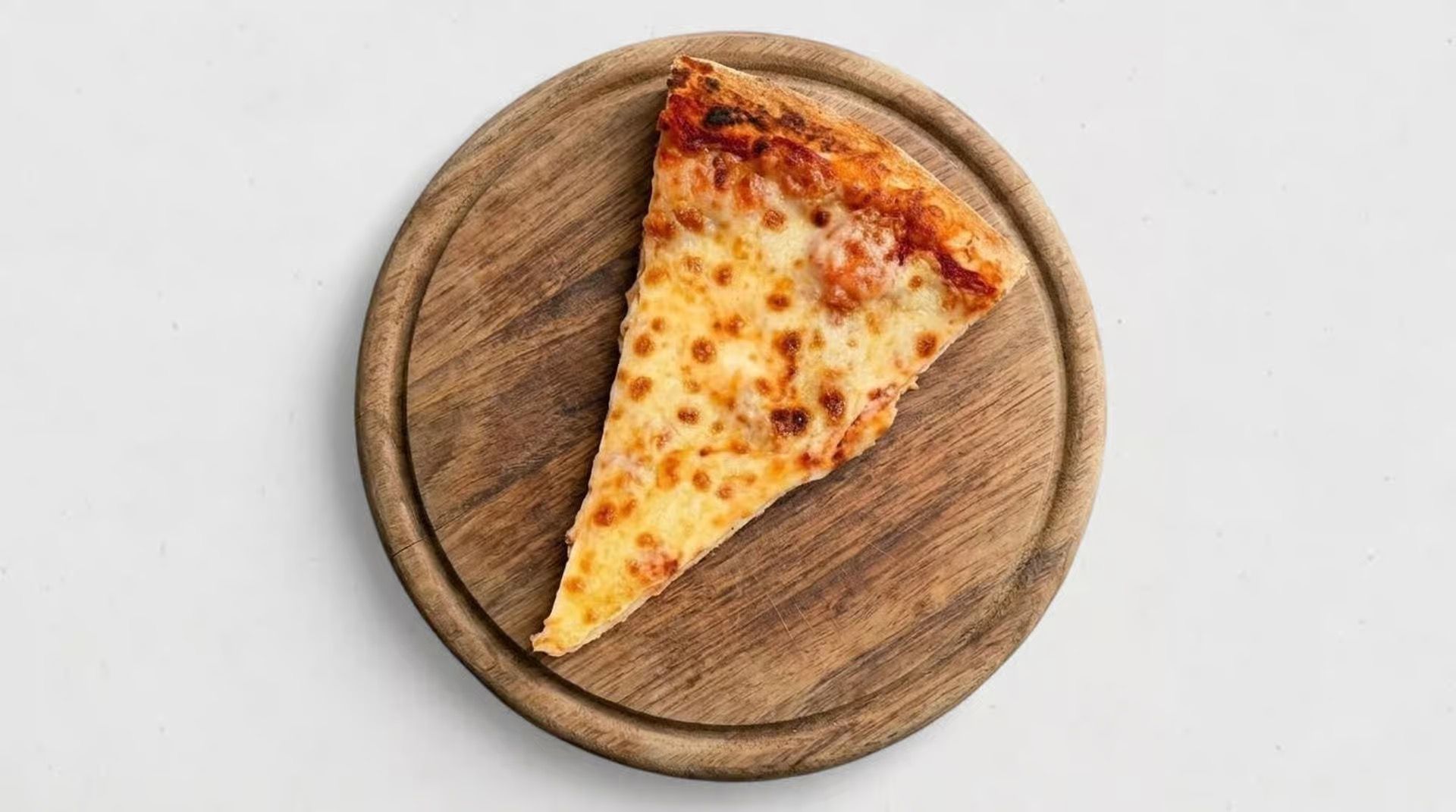 Slice of cheese pizza on a round wooden board against a white background