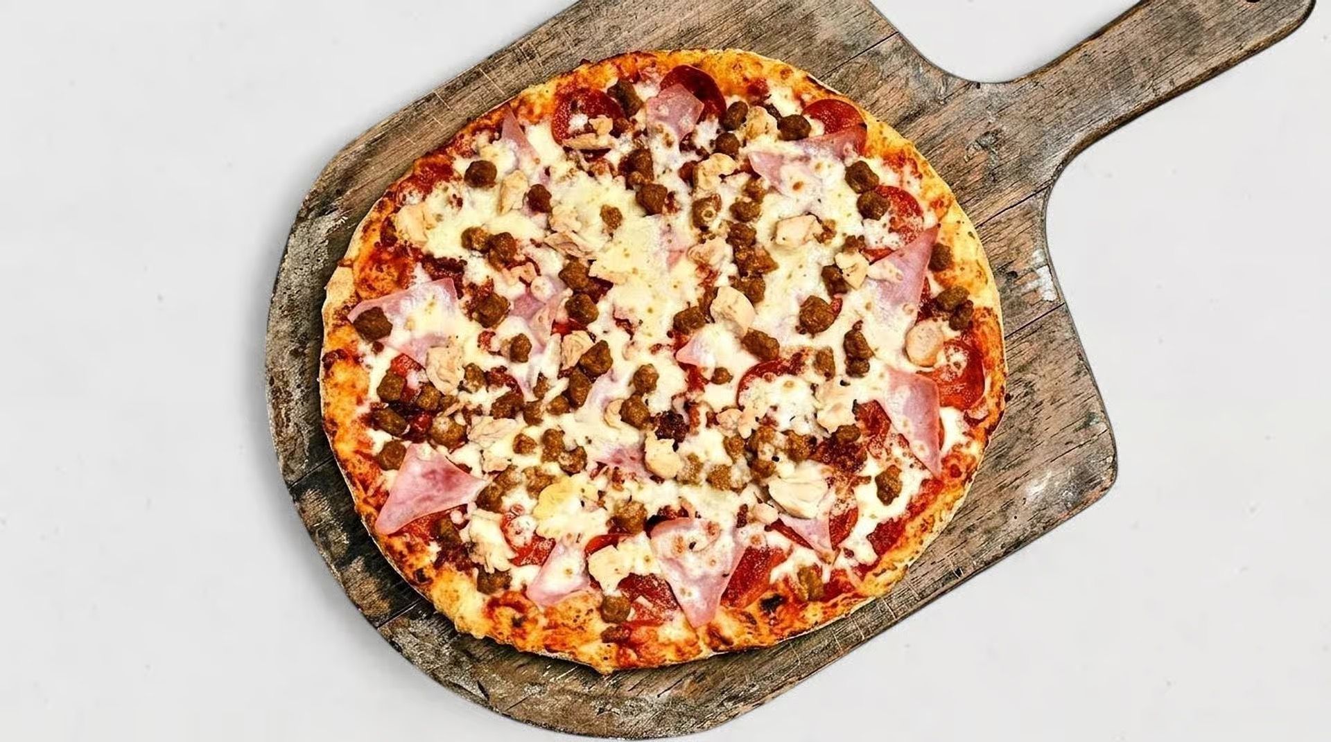 Small pizza on a wooden peel, topped with cheese and pepperoni against a white background