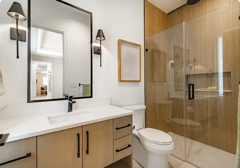 Modern bathroom with wood vanity, large mirror, toilet, and glass shower enclosure