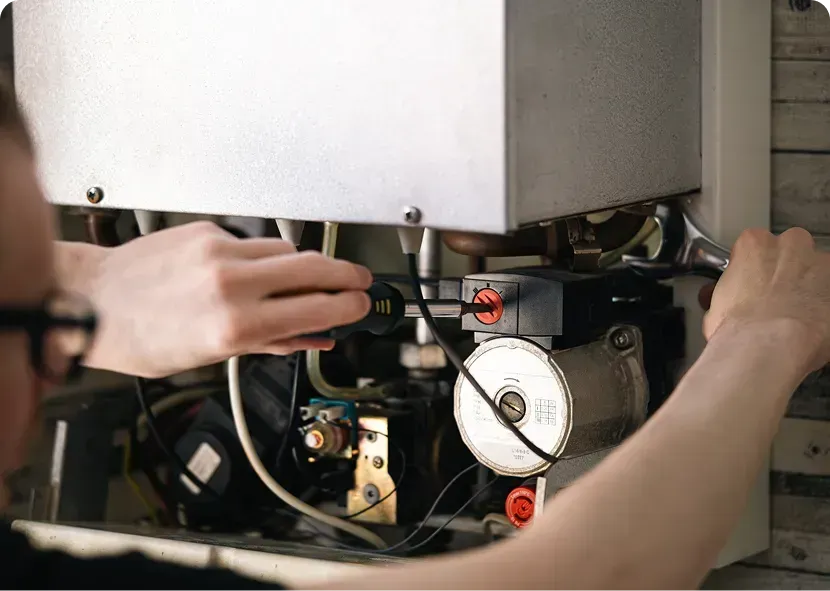 Hands adjusting the underside of a machine with wires and a pressure gauge exposed