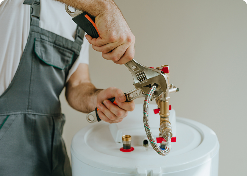 Hand using pliers to attach a brass fitting to a white tank with red-capped ports