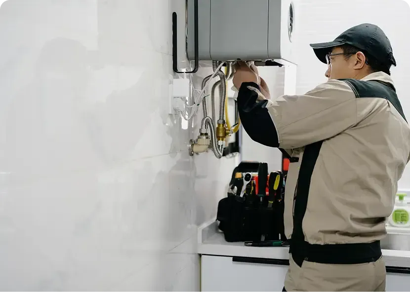 Technician servicing wall-mounted equipment in a white utility room