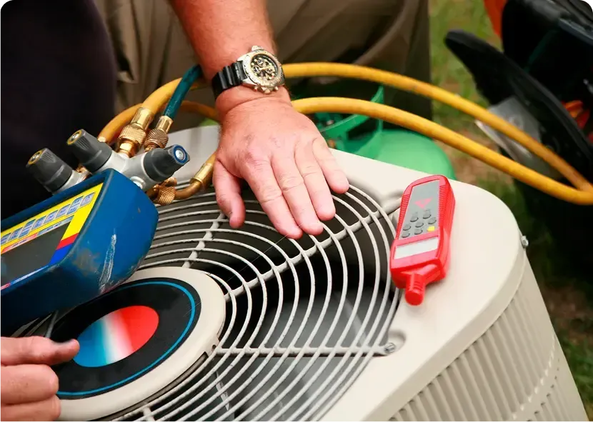 Technician checking an outdoor HVAC unit with gauges and hoses attached