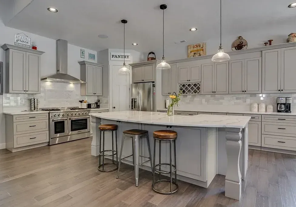 Bright modern white kitchen with island, bar stools, and stainless steel appliances