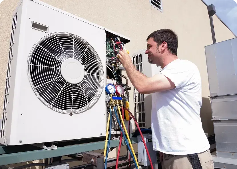 Technician repairing an outdoor HVAC unit with tools and gauges.