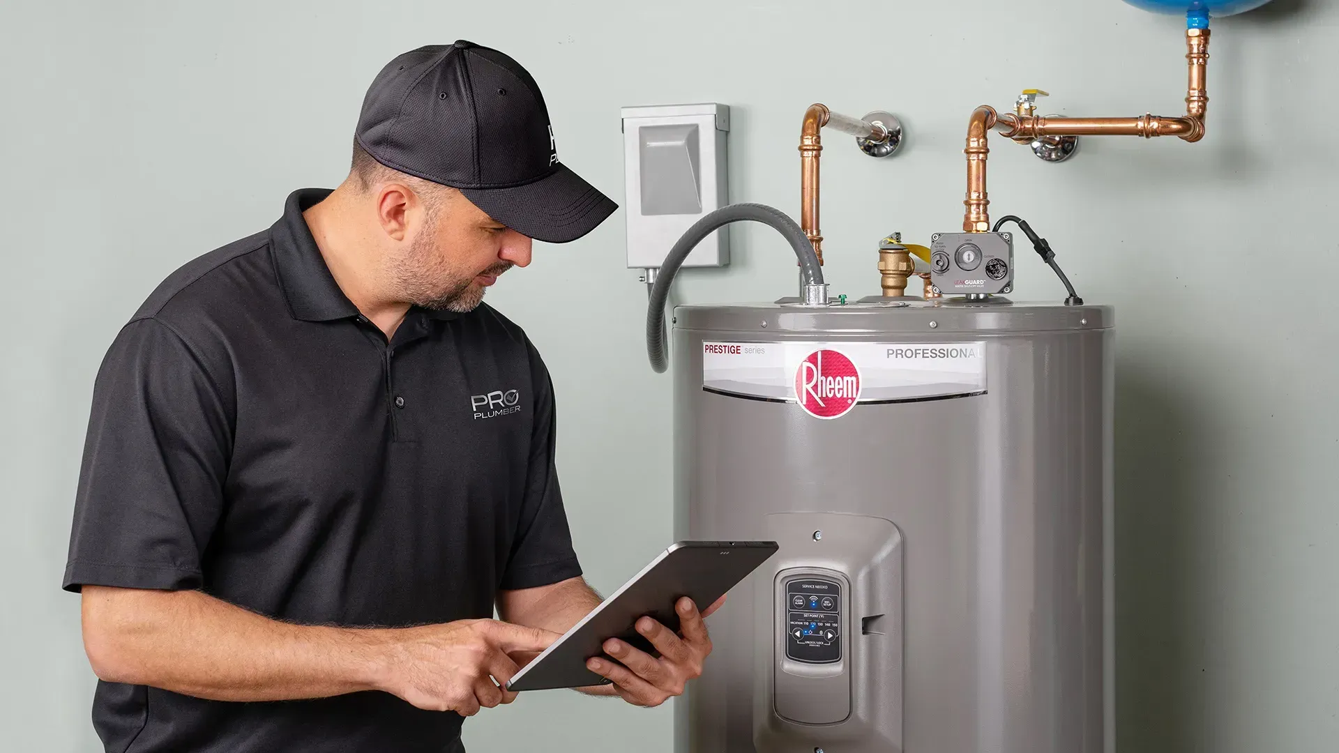 Technician using a tablet beside a gas water heater in a utility room