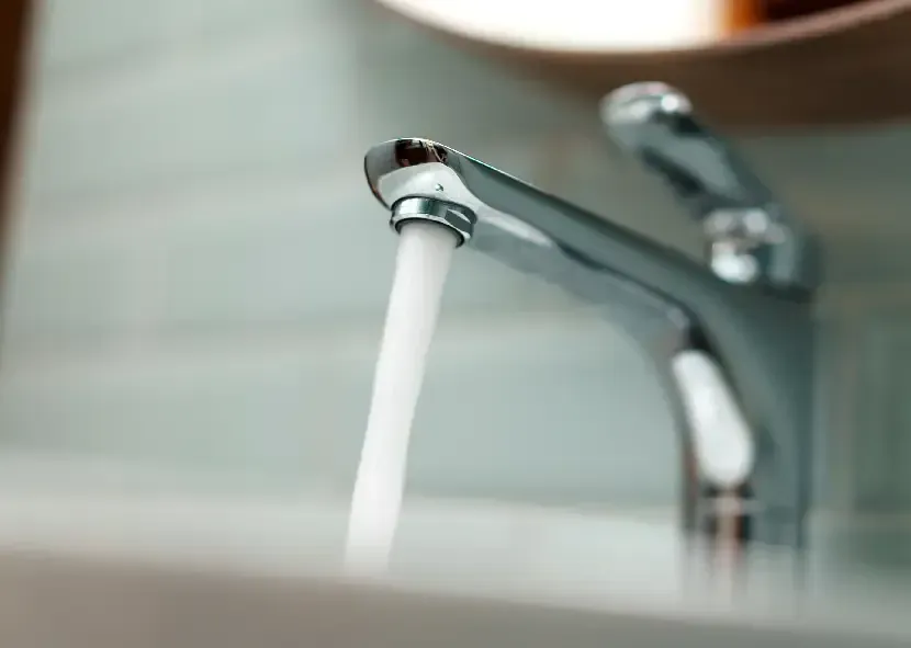 Chrome faucet running water over a bathroom sink