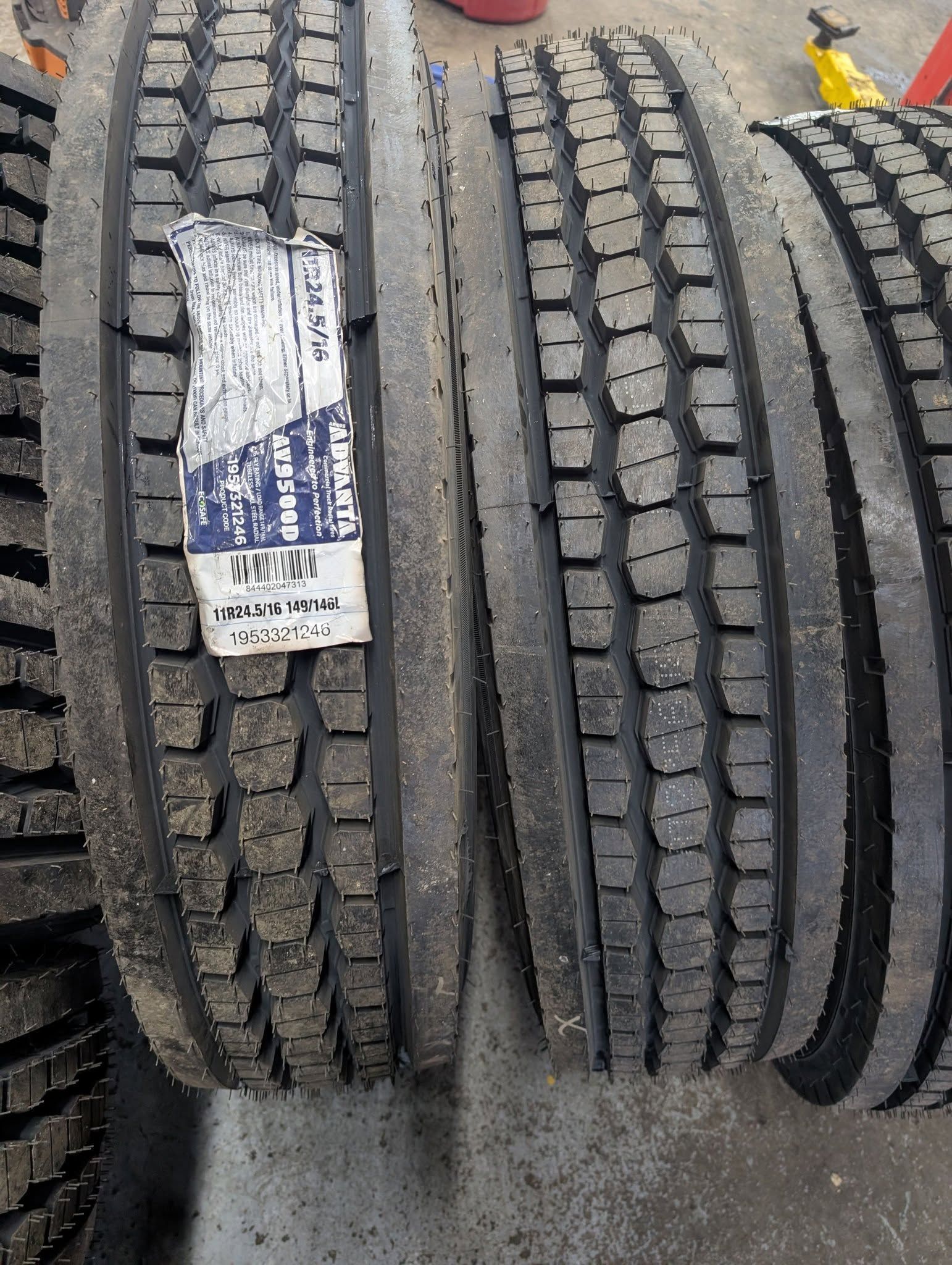 Tire shop display of stacked heavy-duty truck tires with worn tread patterns and a hanging label