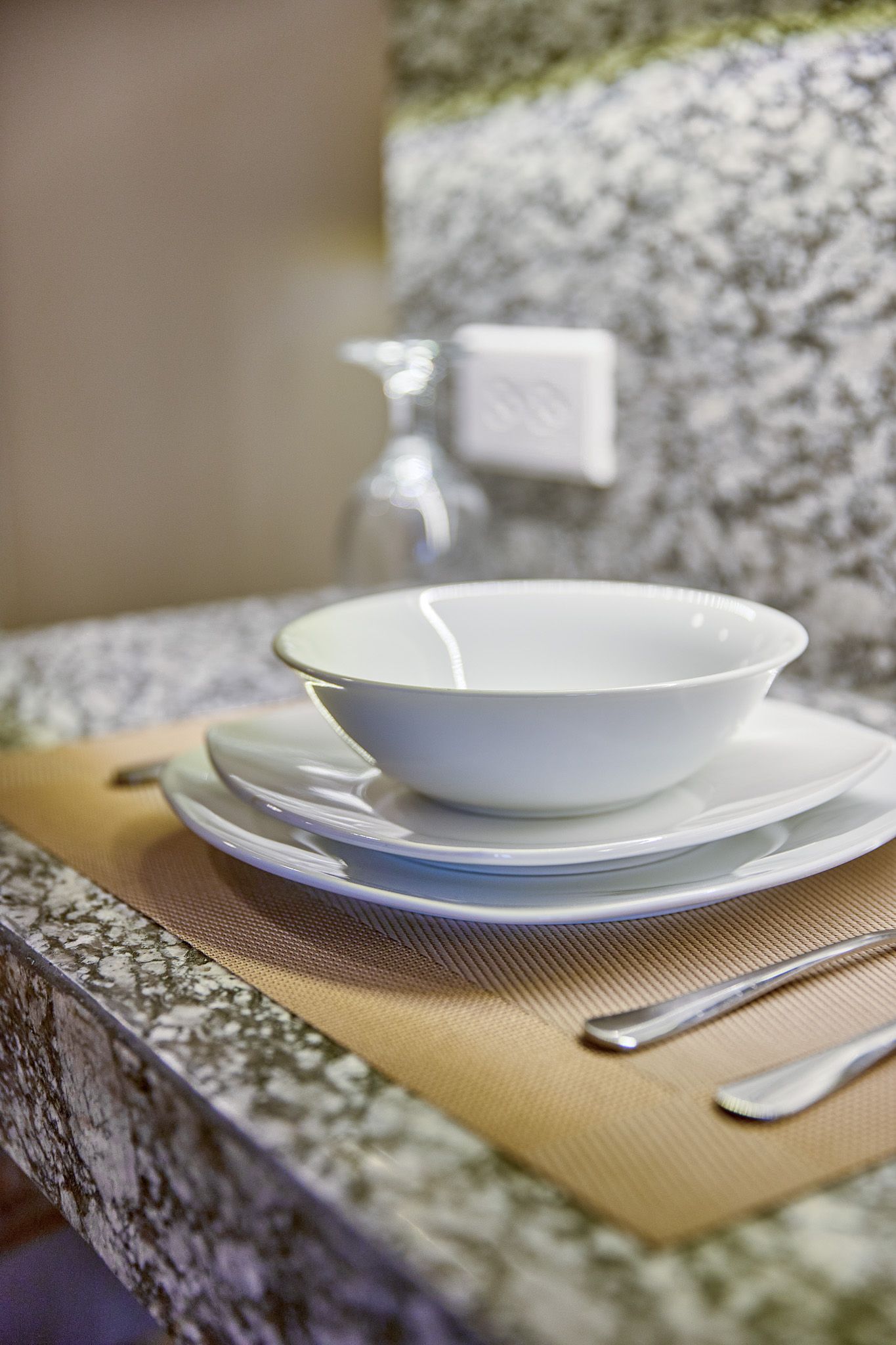 White ceramic bowl and plates on gold placemat with silverware