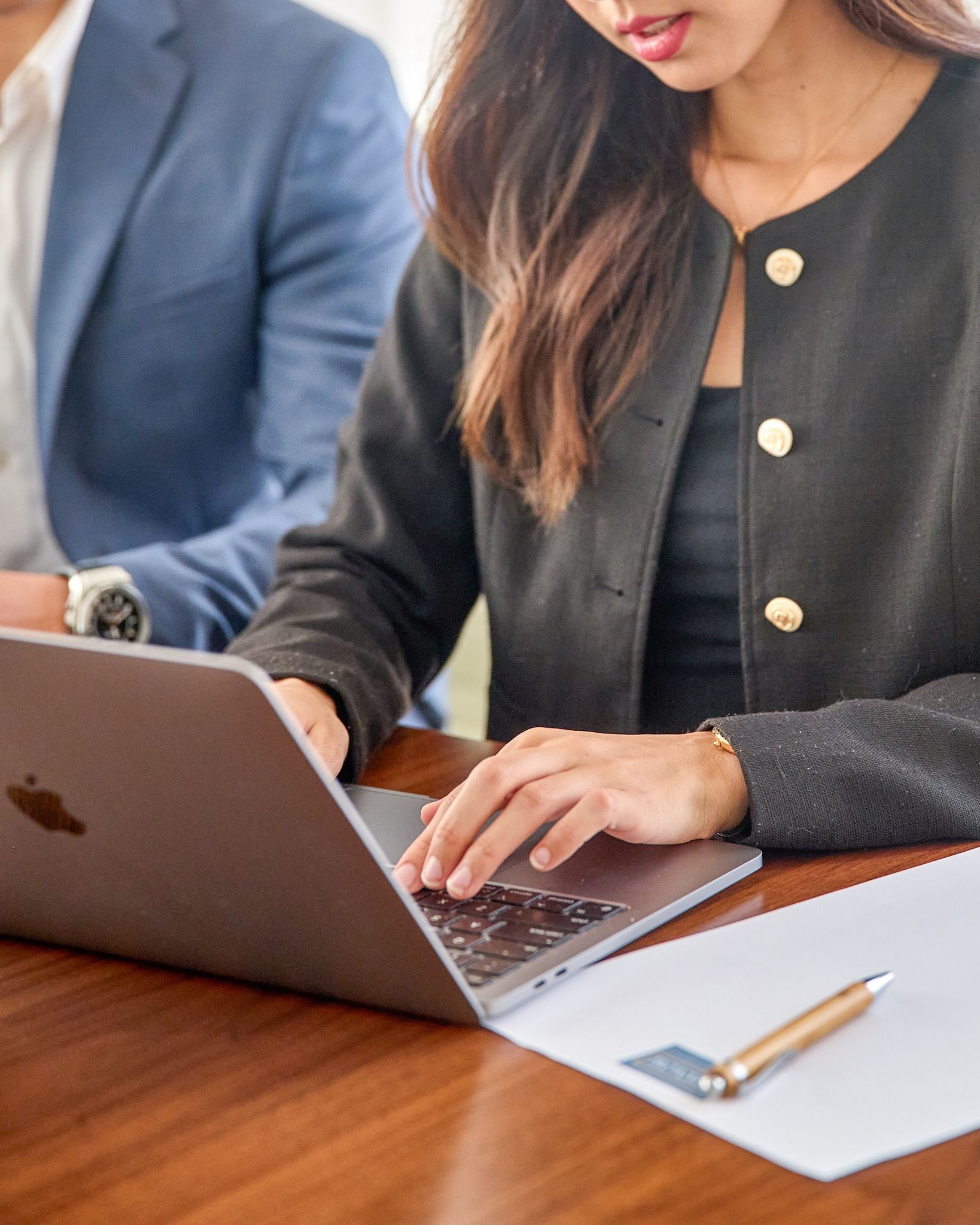 A woman in a black jacket is typing utilizing The Connor Services Residences Function Room.