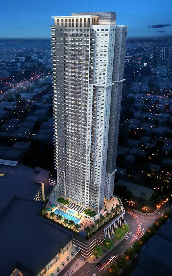 High-rise apartment building with a pool, lit up at night, over a city landscape.