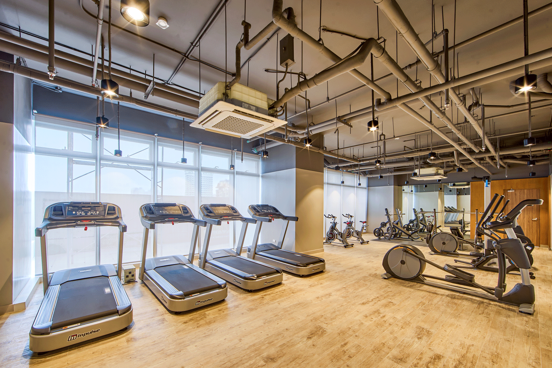 Well-equipped fitness center at The Connor at Greenhills featuring premium cardio machines, spin bikes, windows