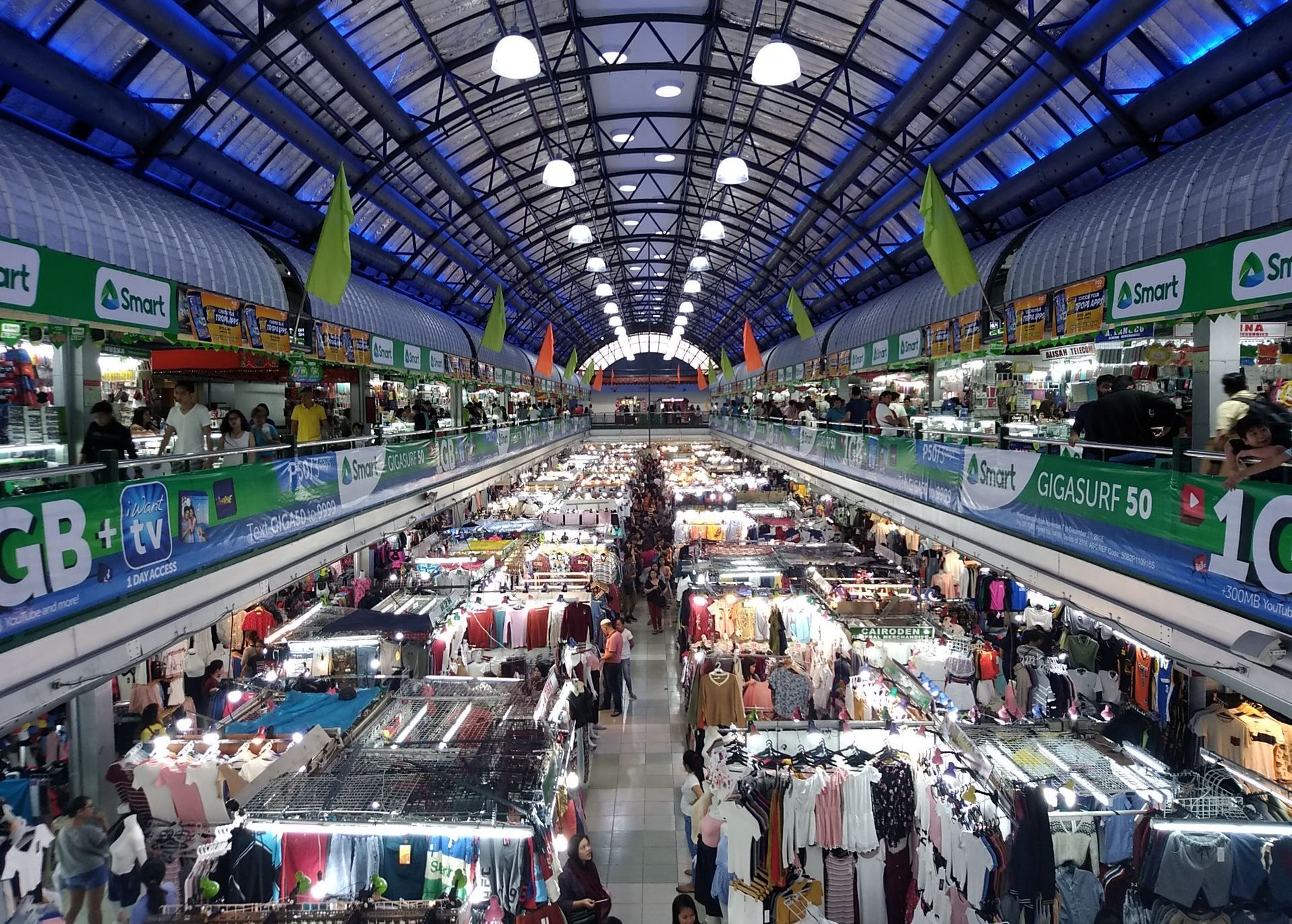 Busy indoor market hall with many stalls under a high arched glass roof.
