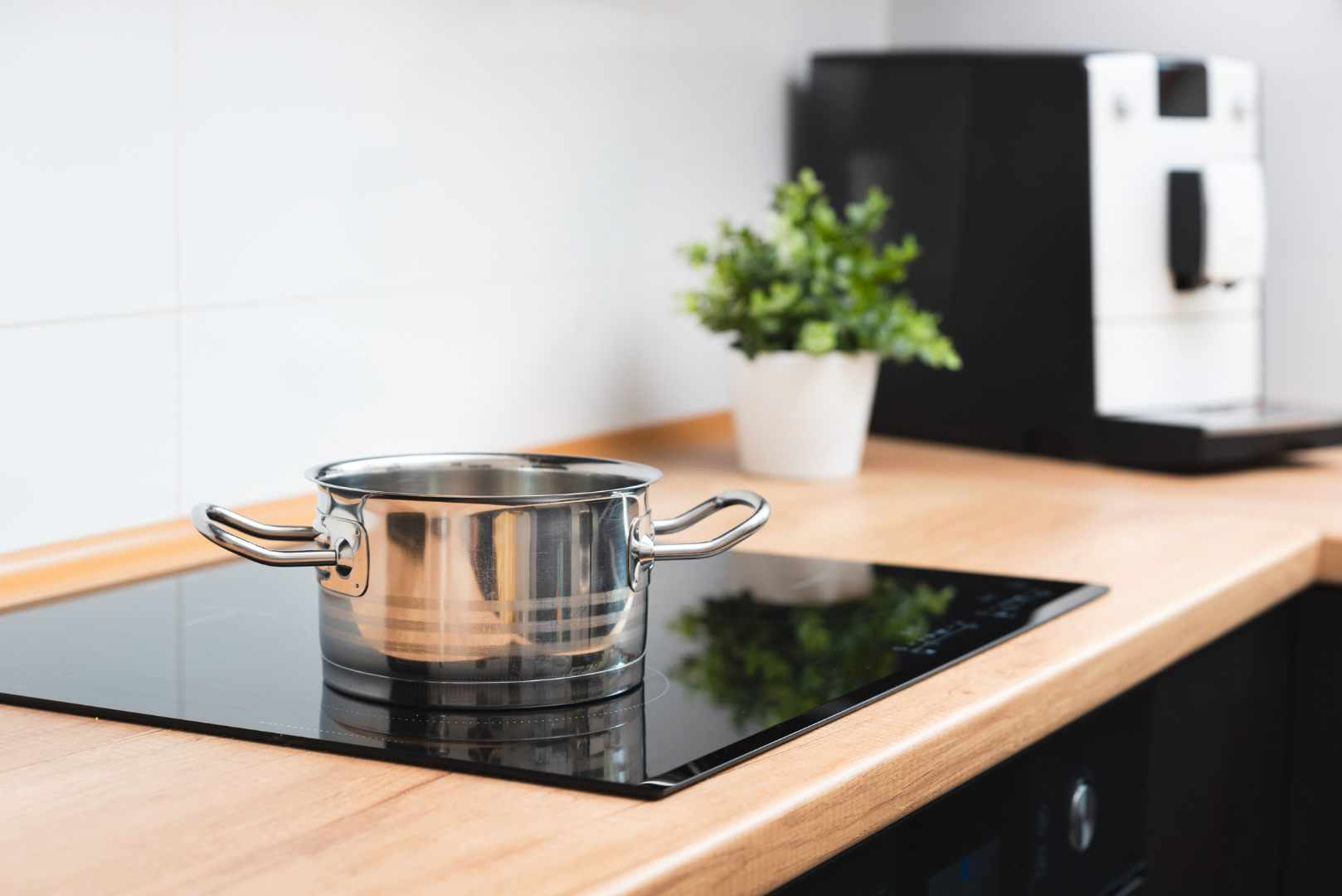 Stainless steel pot on black induction cooktop in modern kitchen