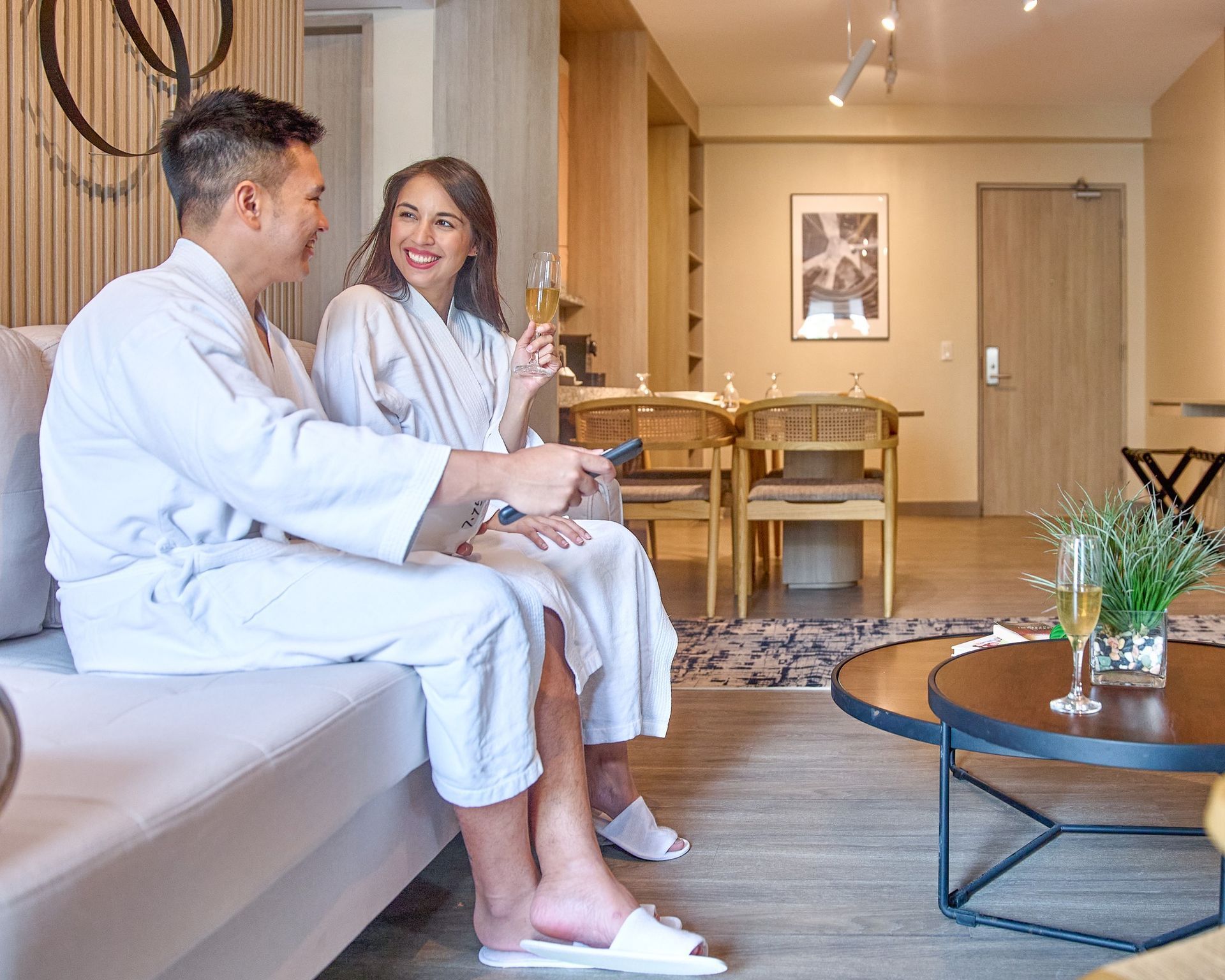 Couple sitting on a sofa in a bright living room, chatting with a coffee table in front of them.