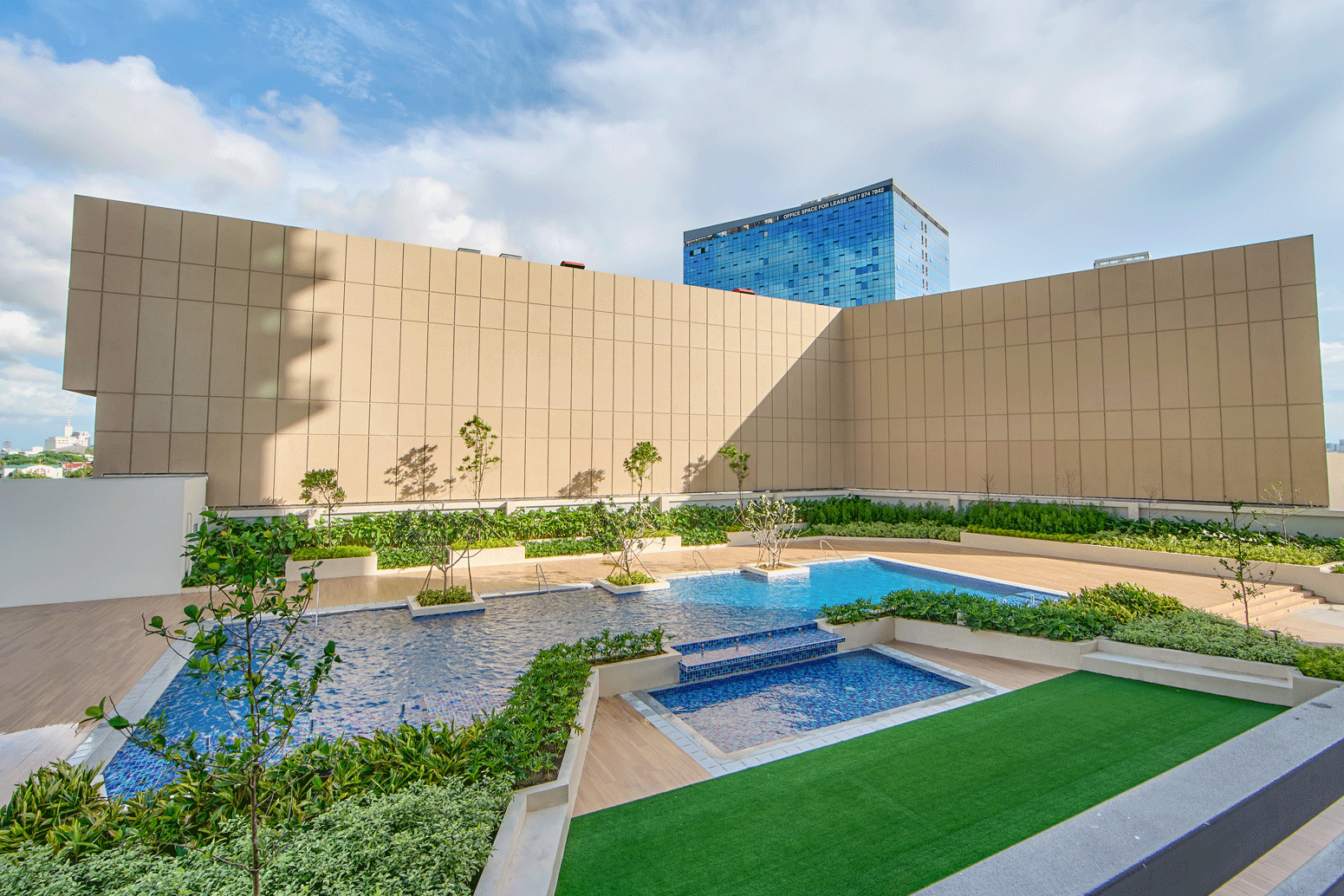 Serene swimming pool deck at The Connor at Greenhills featuring landscaped gardens,  pools, and lush greenery with city views