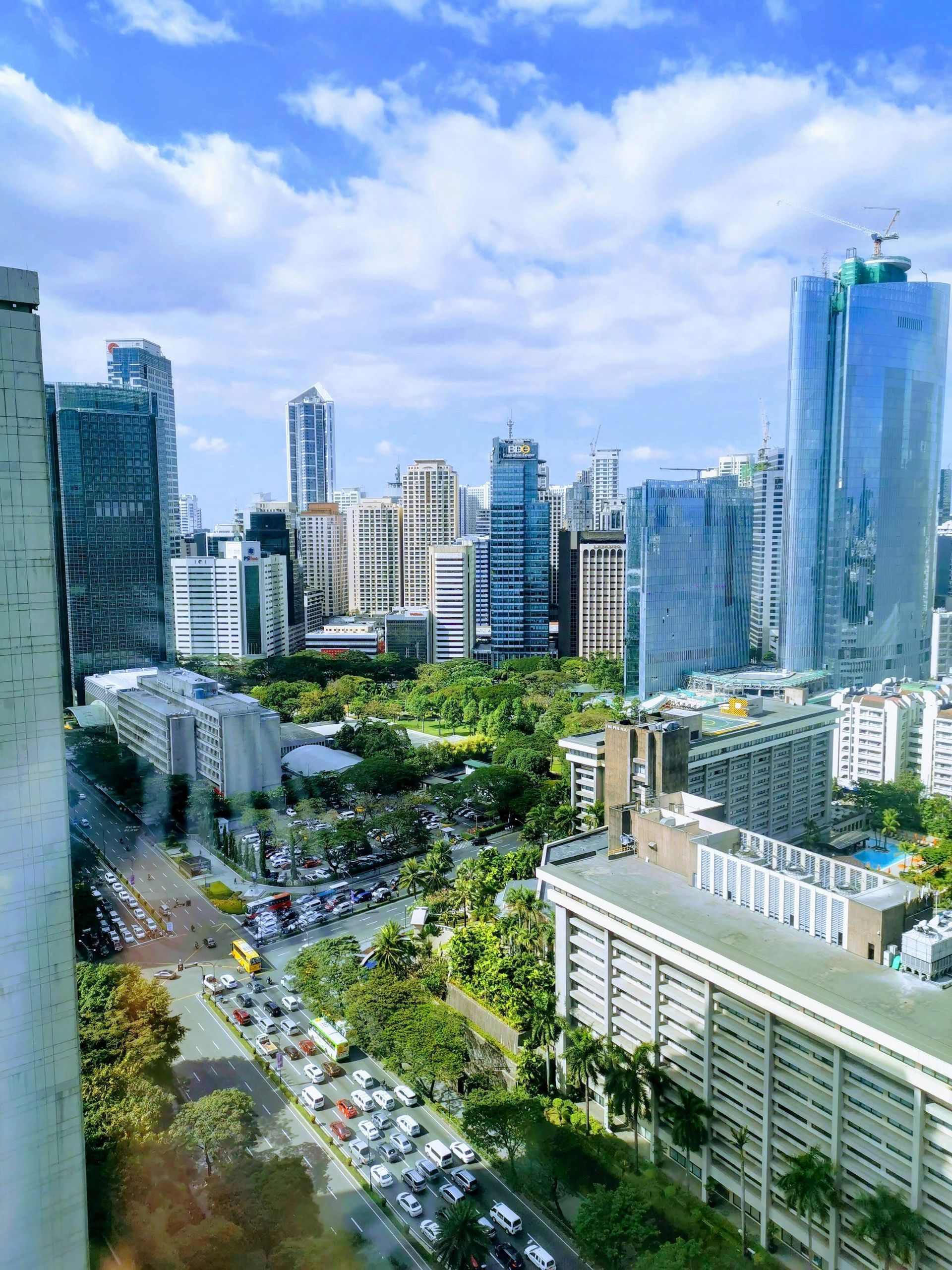 City skyline with tall buildings, green park below, and traffic on a bright blue day