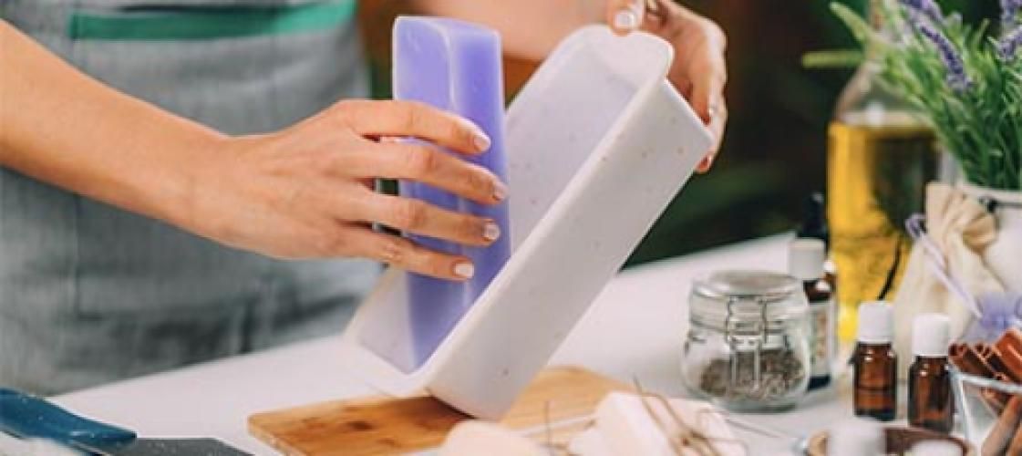 A person is making soap in a mold on a table.