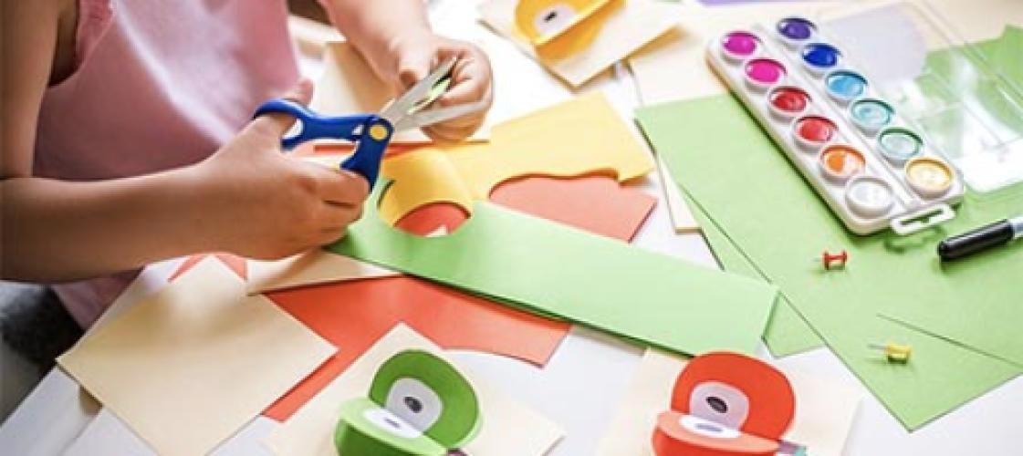 A child is cutting a piece of paper with scissors.