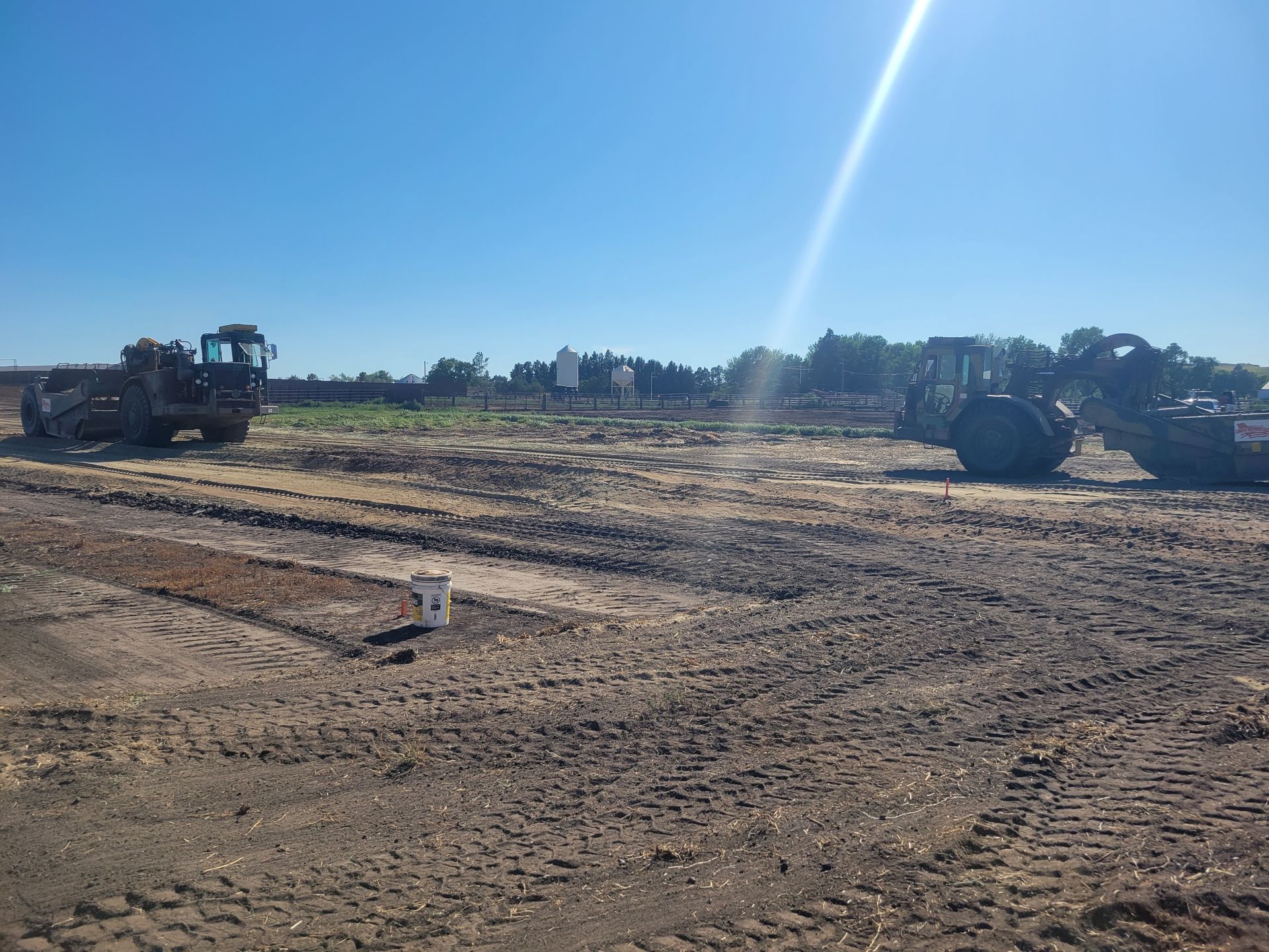 Construction site with heavy machinery on a sunny day. Brown dirt and clear blue sky.
