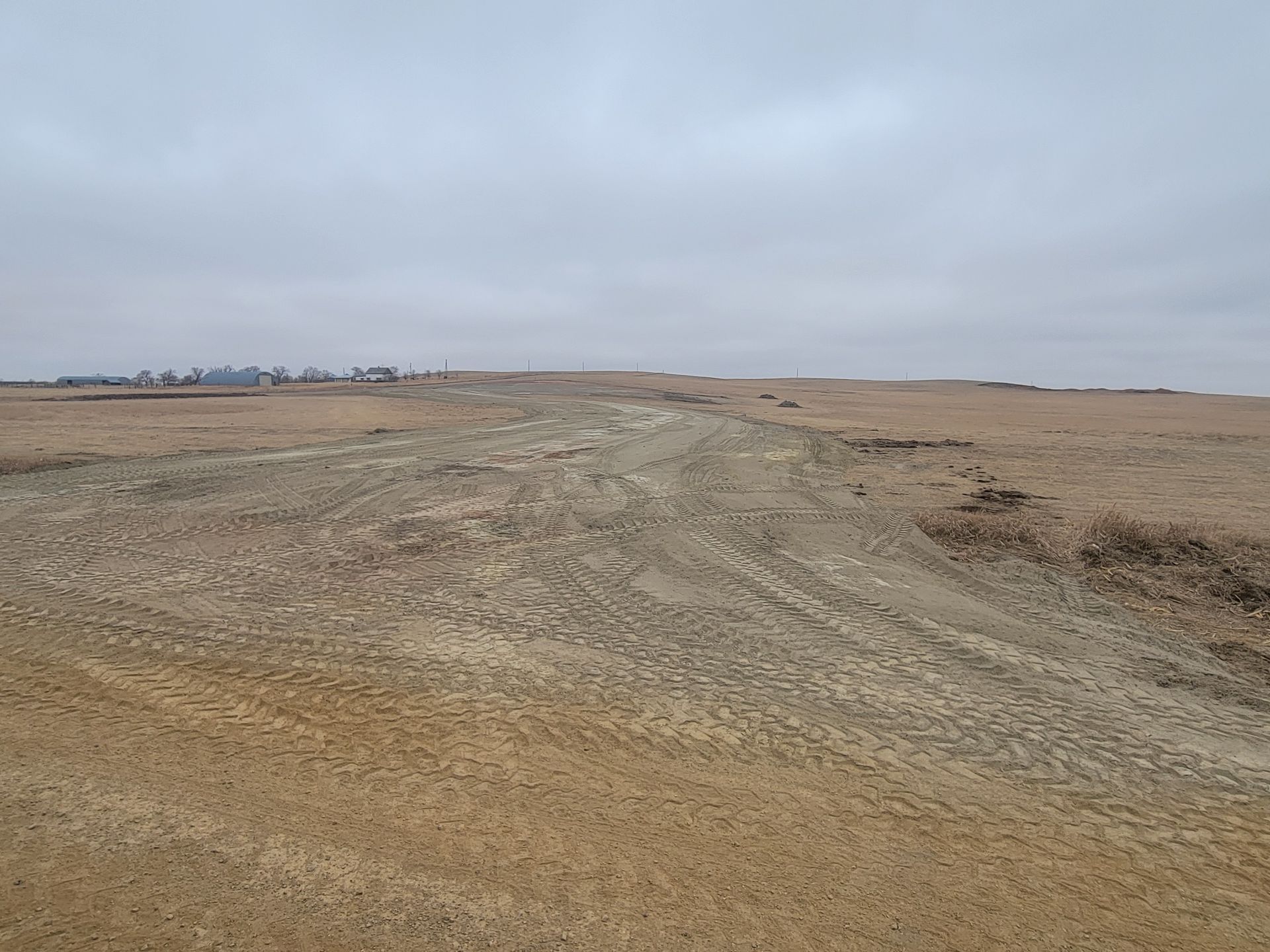 Brown, barren landscape under a cloudy sky, with a distant city skyline.