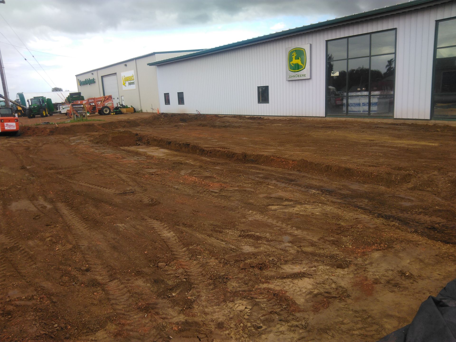 Dirt area in front of a John Deere dealership building under construction.