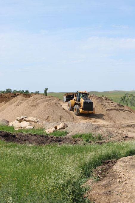 A large yellow bulldozer is parked in a grassy field.