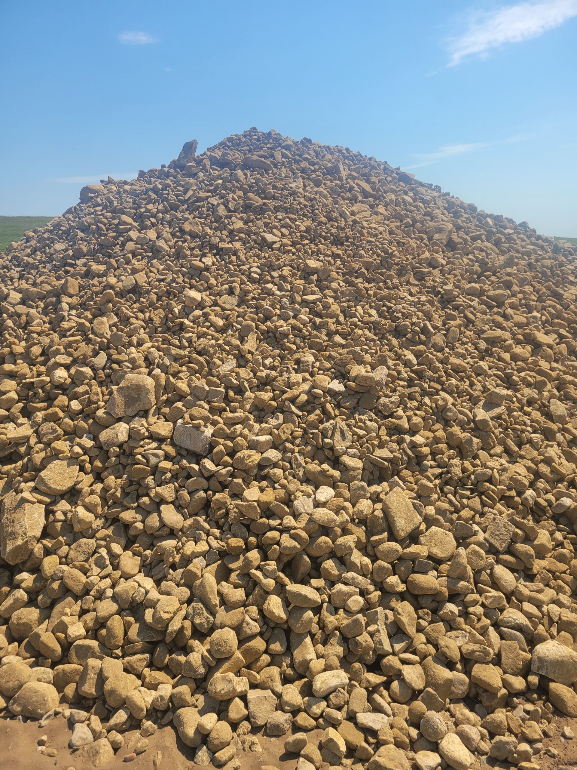 Pile of beige rocks under a clear blue sky.