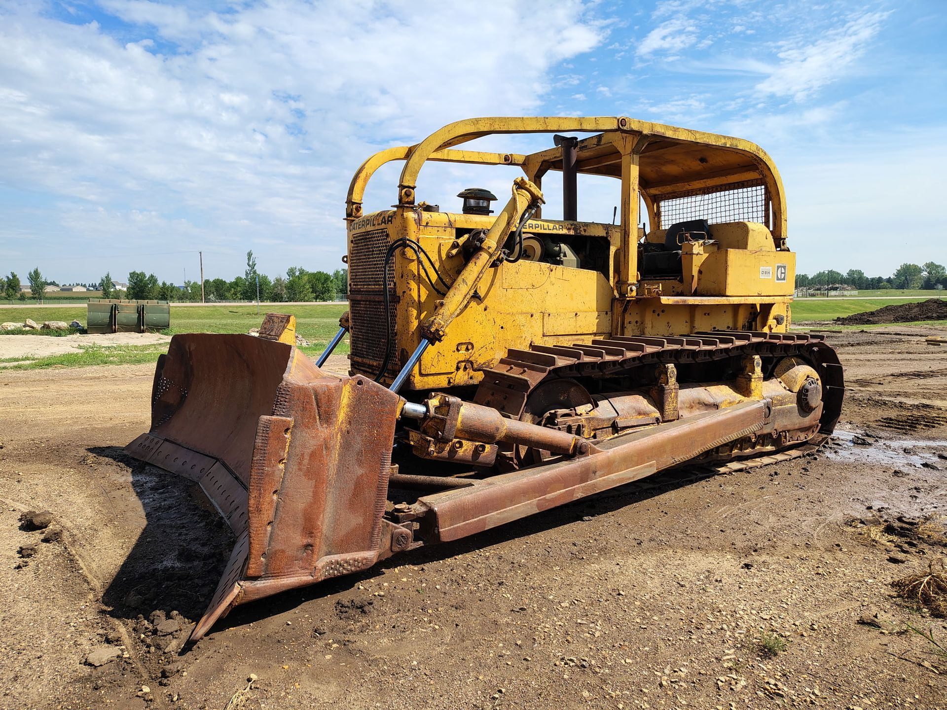Yellow bulldozer on a muddy construction site, under a blue sky.