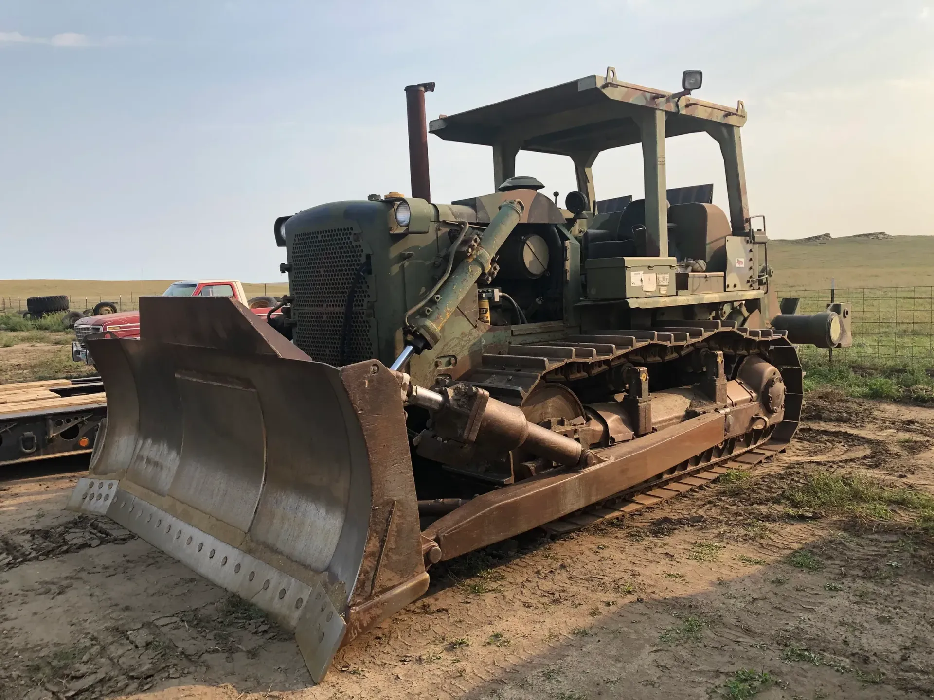 An old bulldozer is parked in the dirt in a field.
