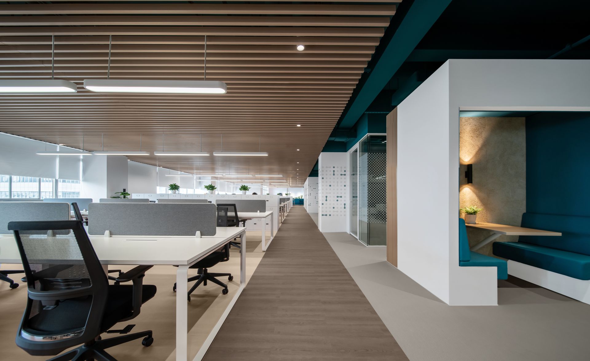 Modern office interior with workstations, meeting rooms, and a teal-colored booth.