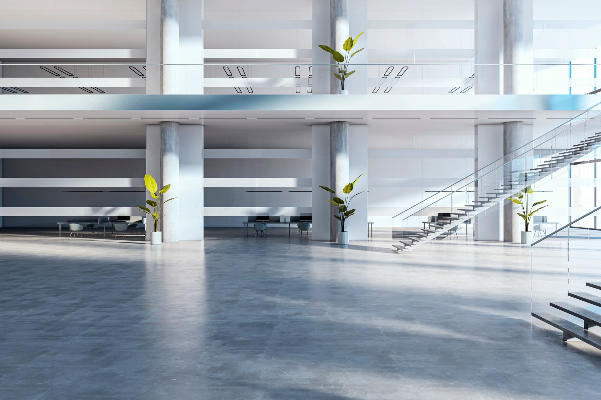 Modern, open-concept office space with white walls, a gray concrete floor, glass staircase, and plants.