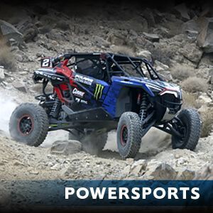 A blue and red atv is driving down a dirt road.