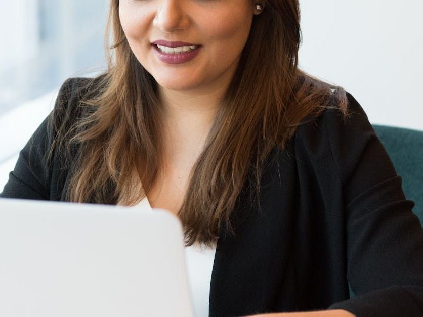 A woman is sitting at a table using a laptop computer.
