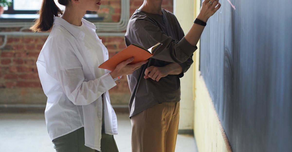 Two women are standing next to each other in front of a blackboard.