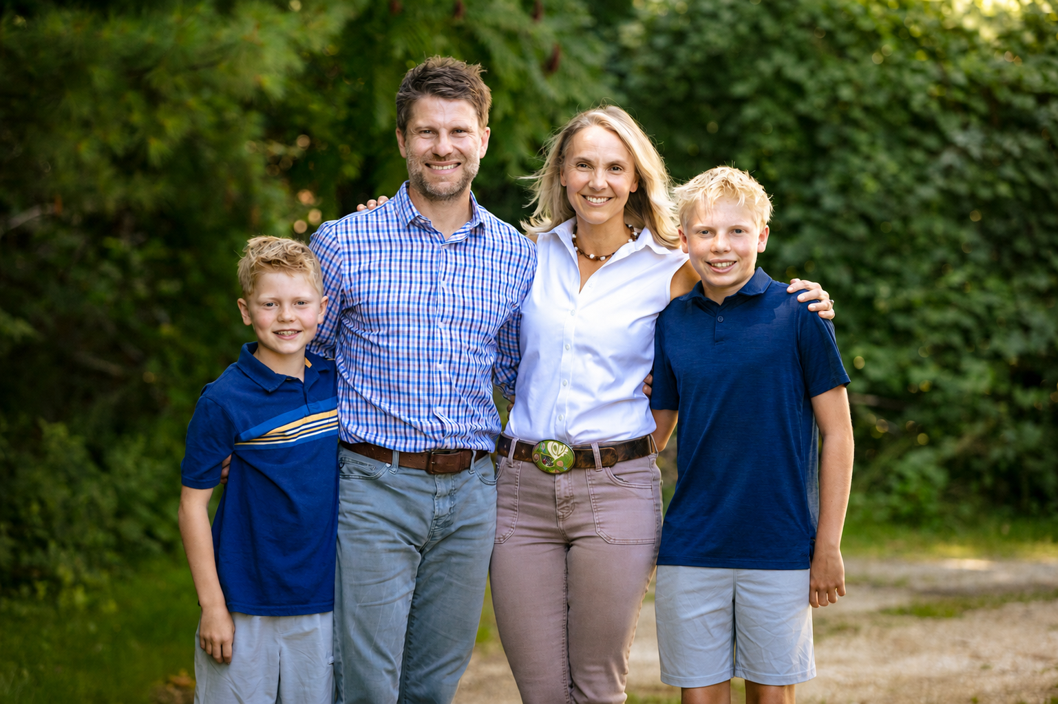 Family of four smiling, posed near a table. 