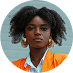 Woman with dark curly hair, wearing orange blazer and large hoop earrings.