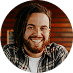 Smiling man with a beard, wearing a plaid shirt.