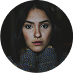 A young woman with dark hair and eyes looking directly at the viewer, with a neutral expression.