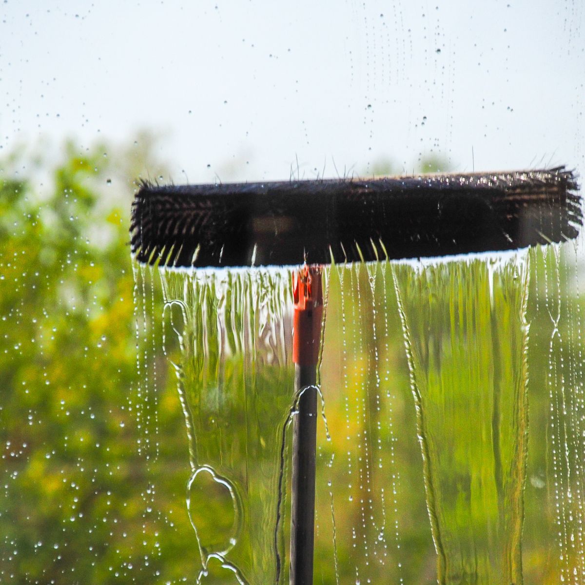 A broom is being used to clean a window.