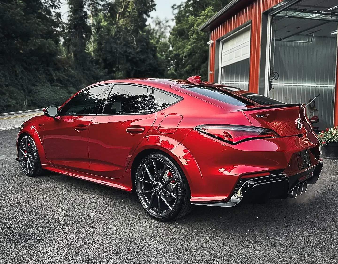 A red car is parked in front of a garage.