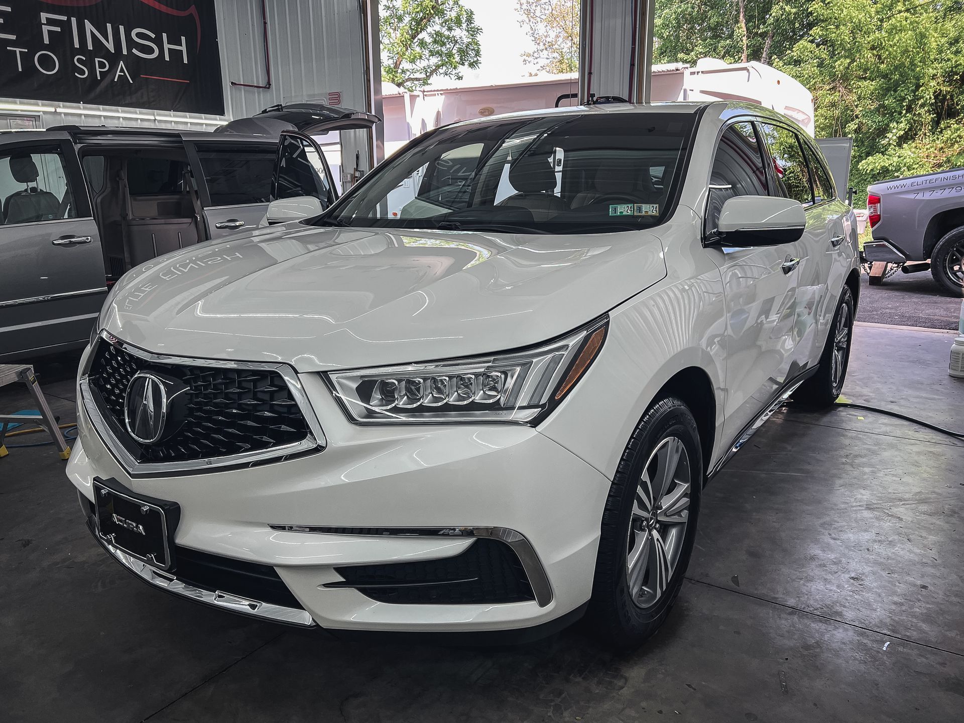 A white acura mdx is parked in a garage.