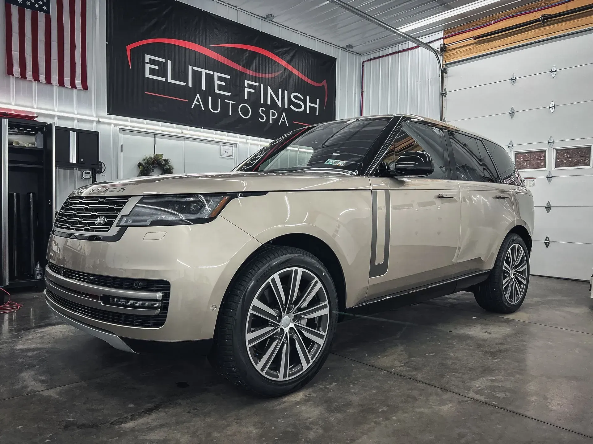 A range rover is parked in a garage next to an american flag.
