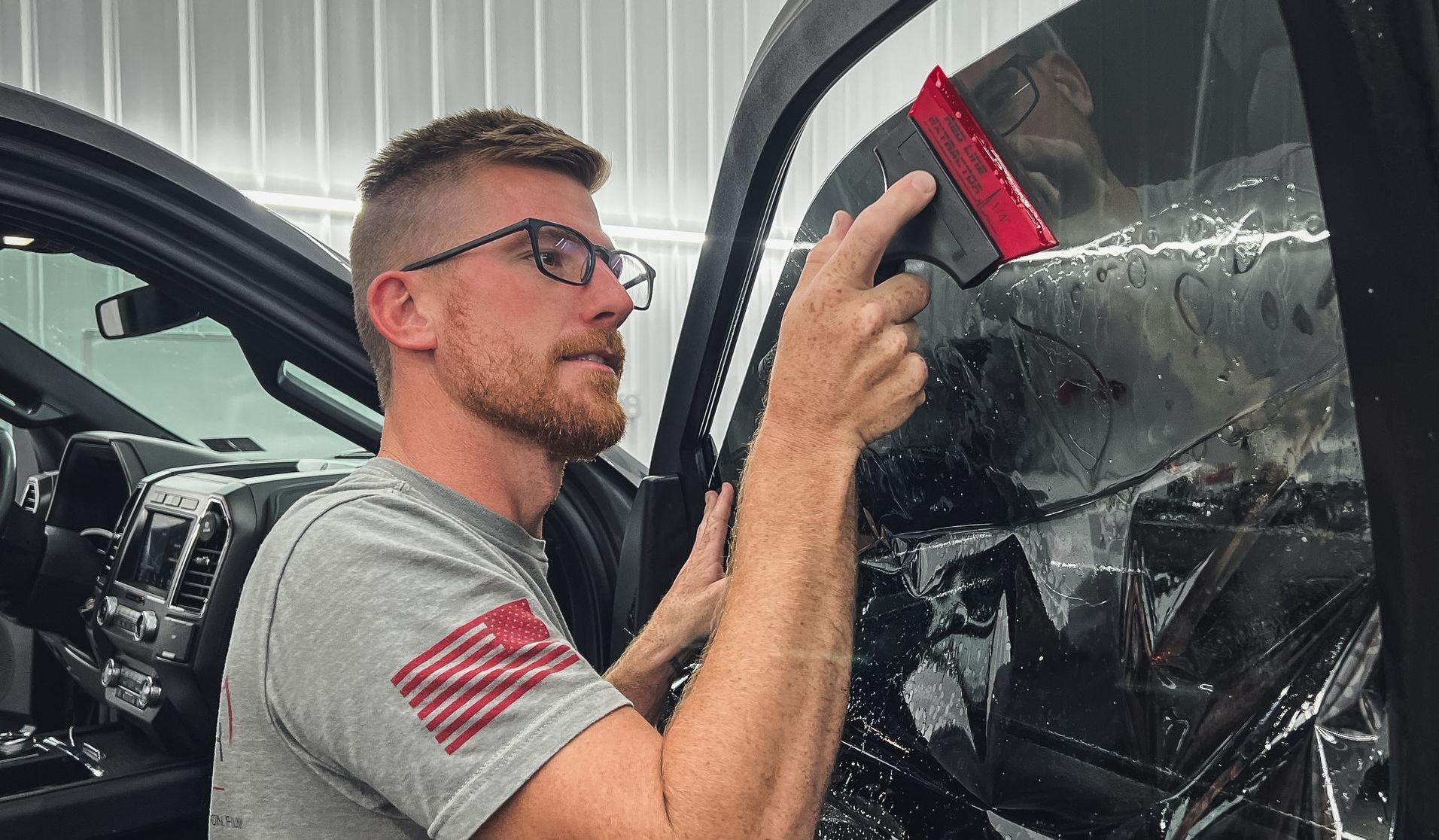 A man is applying window tinting to a car window.