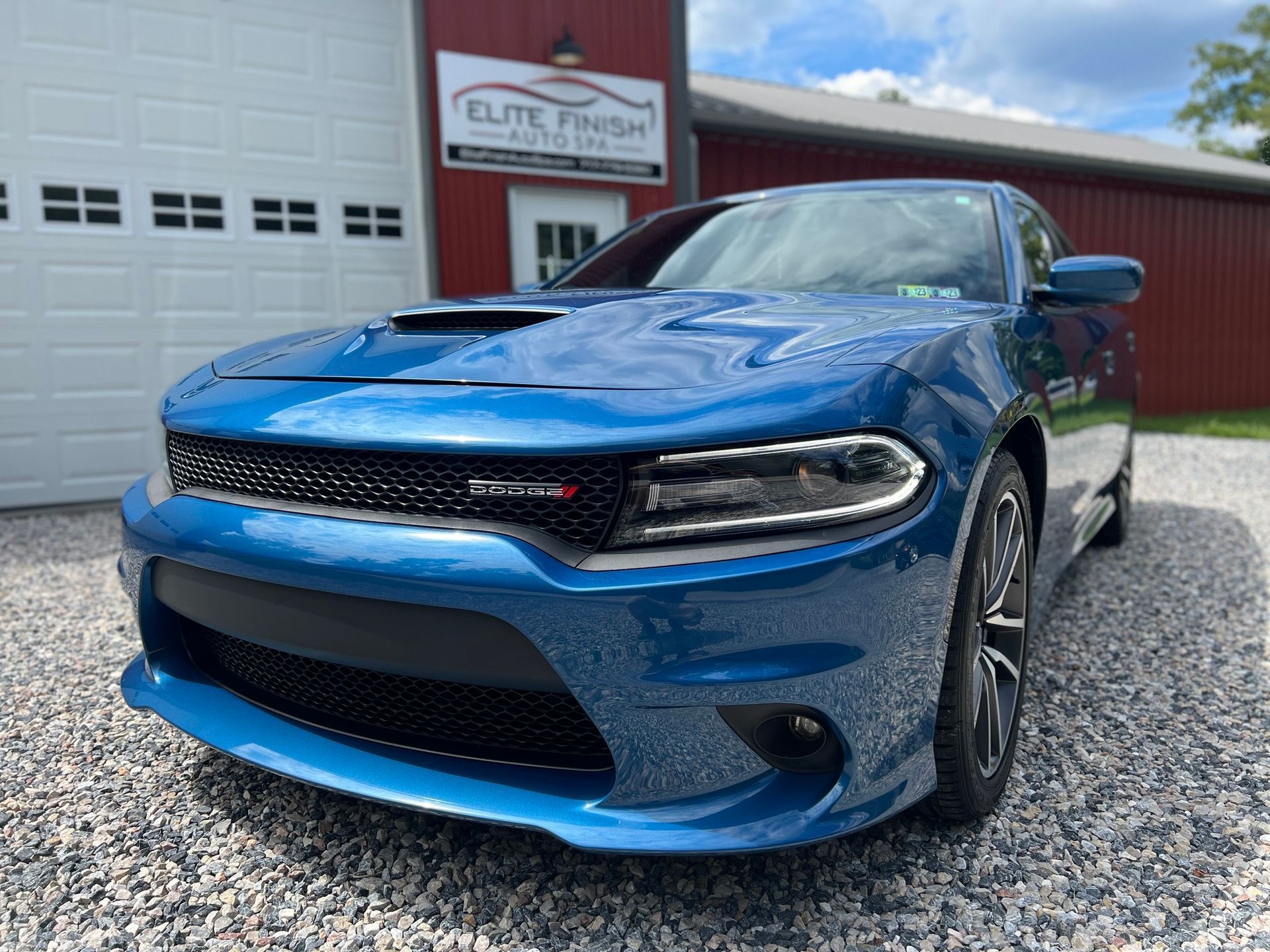 A blue dodge charger is parked in front of a garage door.