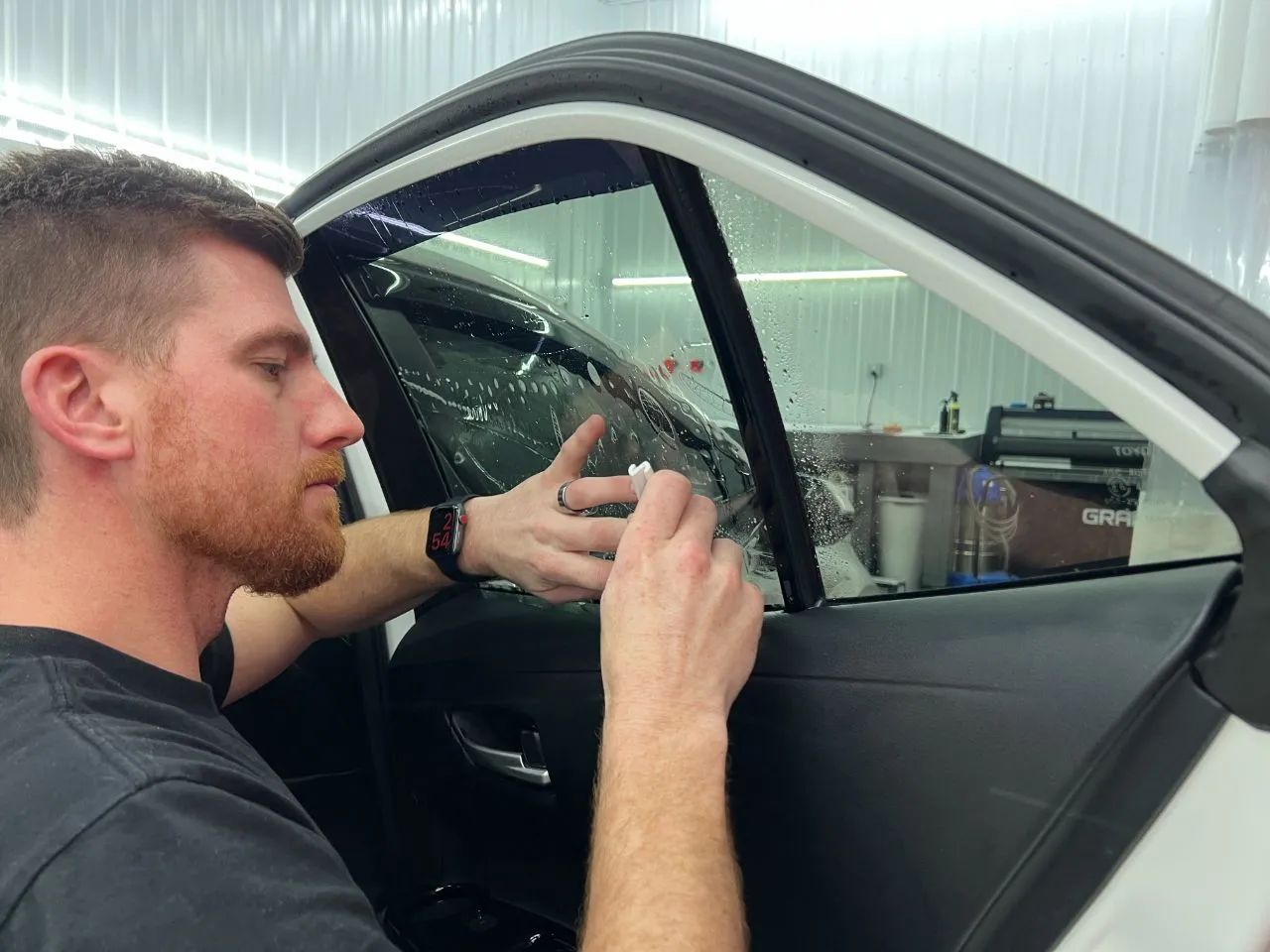 A man is polishing a black suv in a garage.