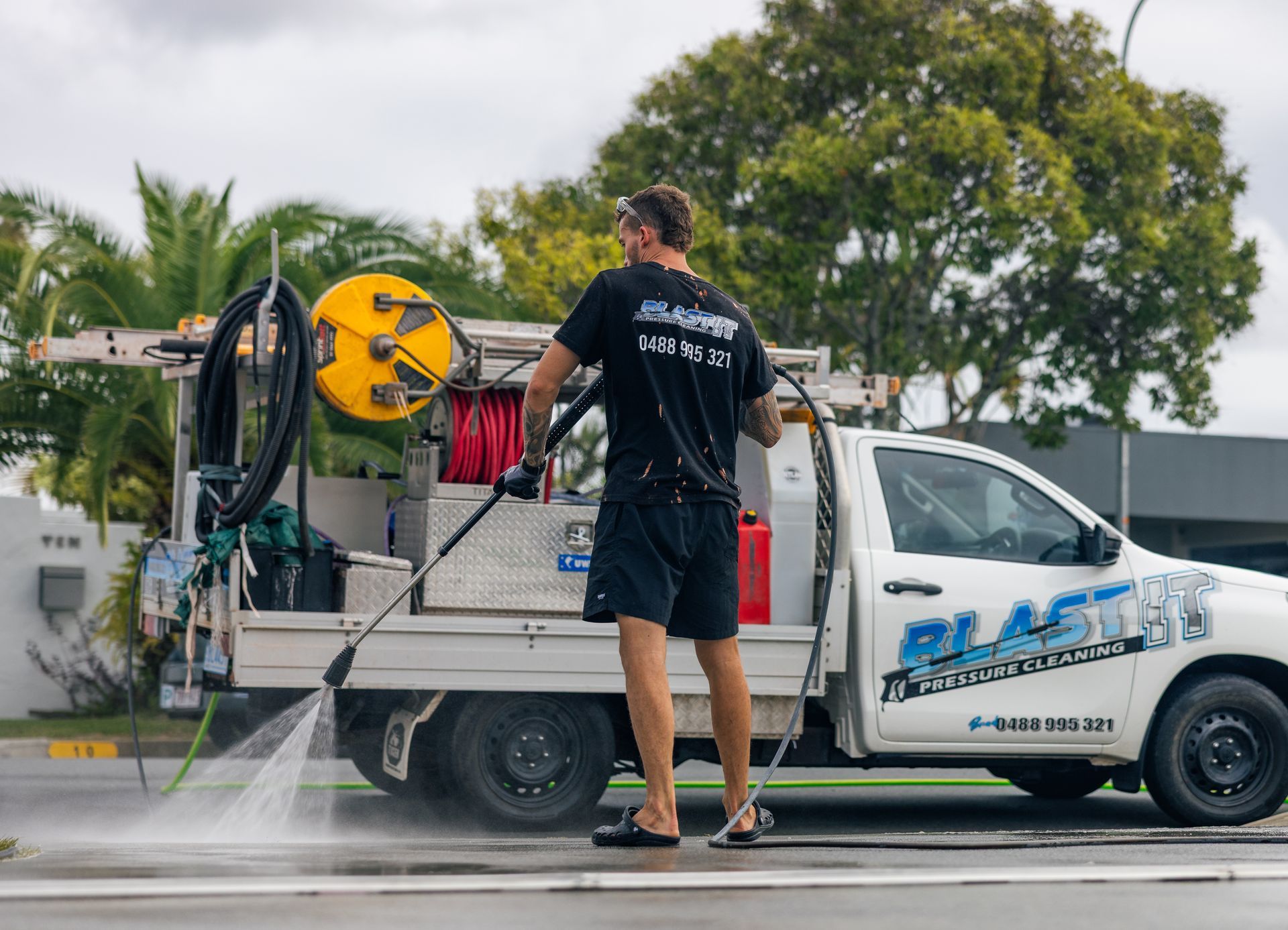 Man pressure washing a street from the back of a white truck. — Blast It Pressure Cleaning - Gold Coast In Gold Coast, QLD