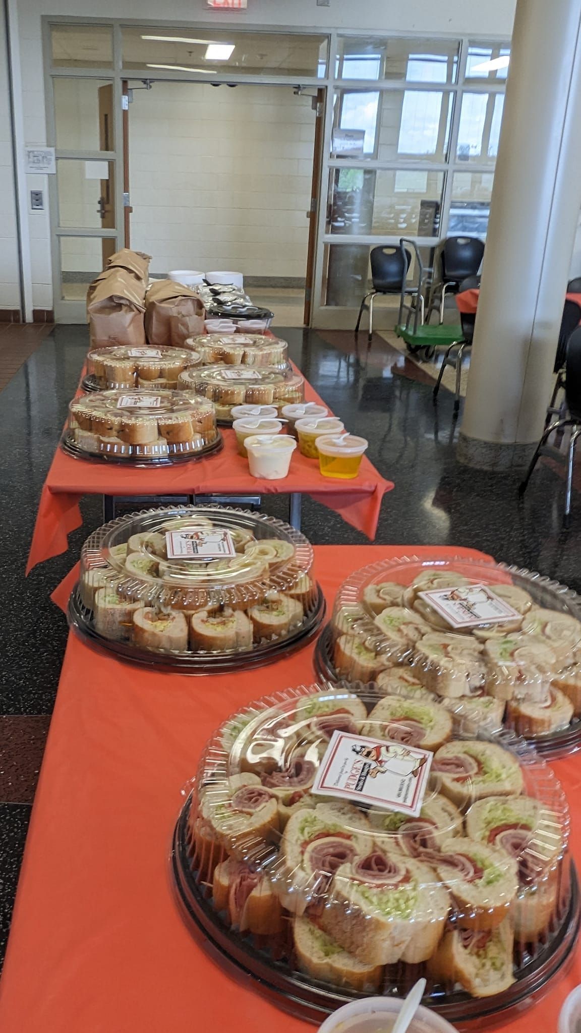 Long table with trays of pastries and baked goods at an indoor event or buffet.